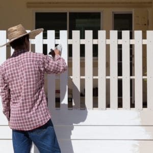 Man painting a fence white