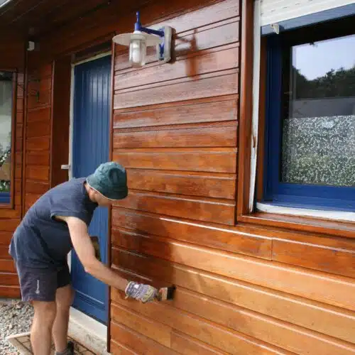 Man using a brush to apply Linitop Classic to house cladding