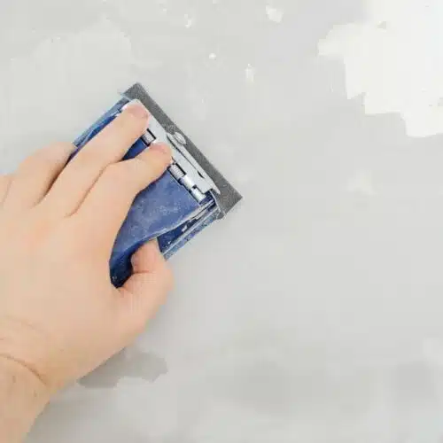 Man sanding a wall