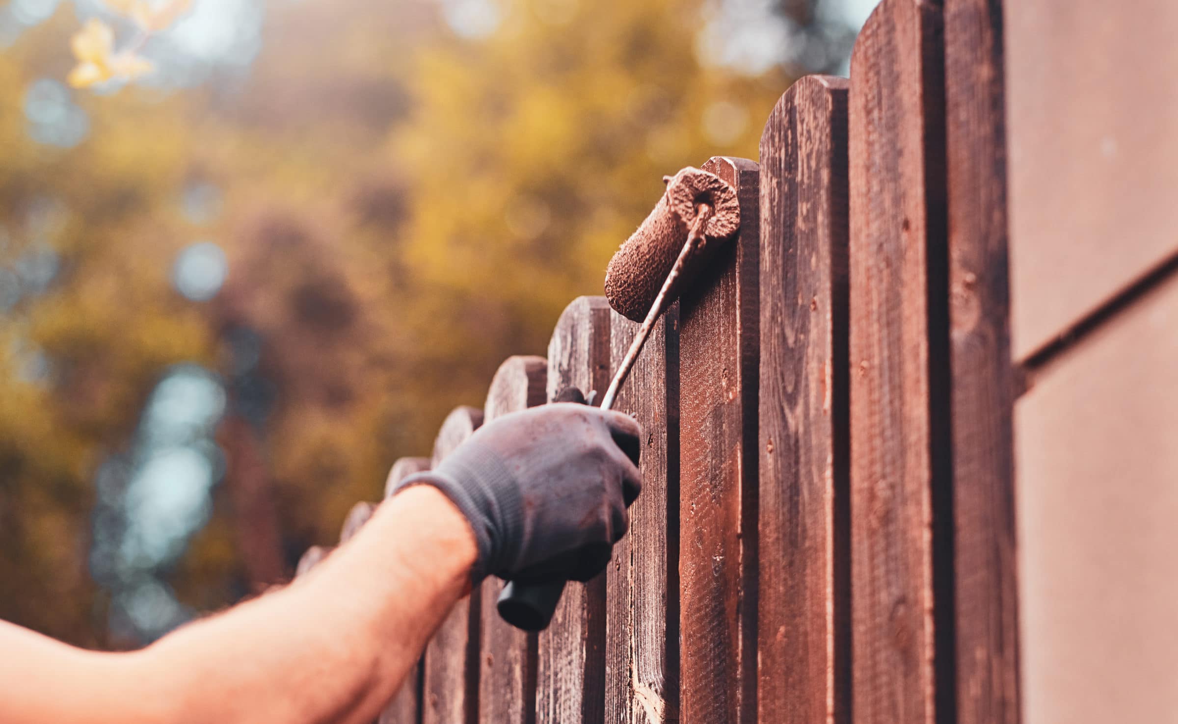 Person using a roller to paint a fence