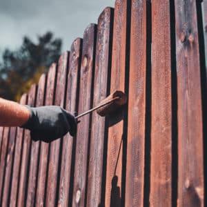person painting a fence on a cloudy day