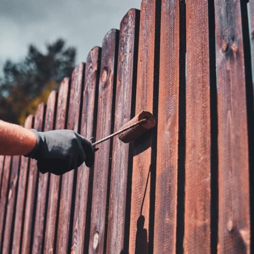 person painting a fence on a cloudy day
