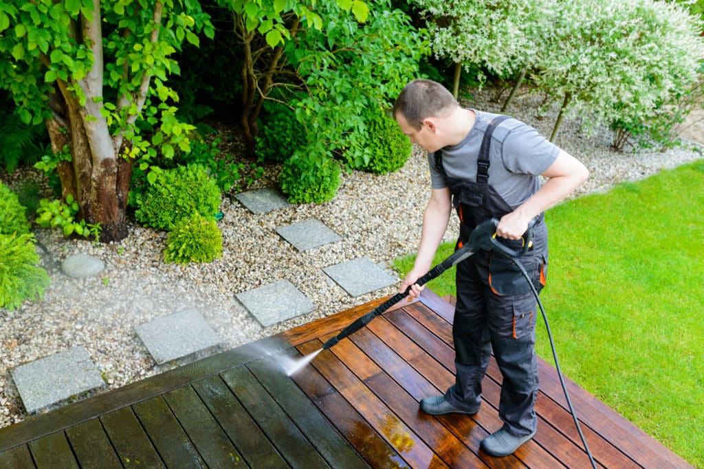 Man power washing a garden deck