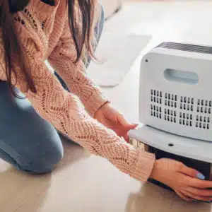 Lady emptying water container of a dehumidifier.